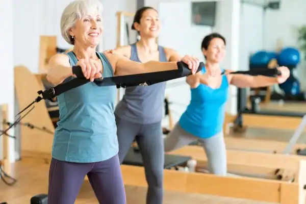 Toning Arms After 60: Empowering Womens Fitness Through Effective Weight Training 2 older woman doing weight training Dover and resistance in the gym to tone upper arms