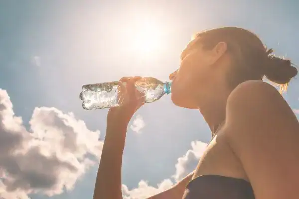 Hydration: The Secret Ingredient for a Toned Stomach and Enhanced Fitness 3 Image of woman drinking water to hydrate Dover after run.